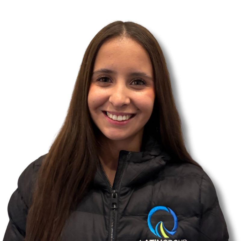 A woman with long brown hair smiles while wearing a black jacket featuring the vibrant logo of Latin Grup on the left side. The background is white.